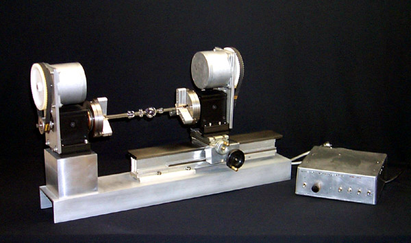 A stepper motor drives each headstock.